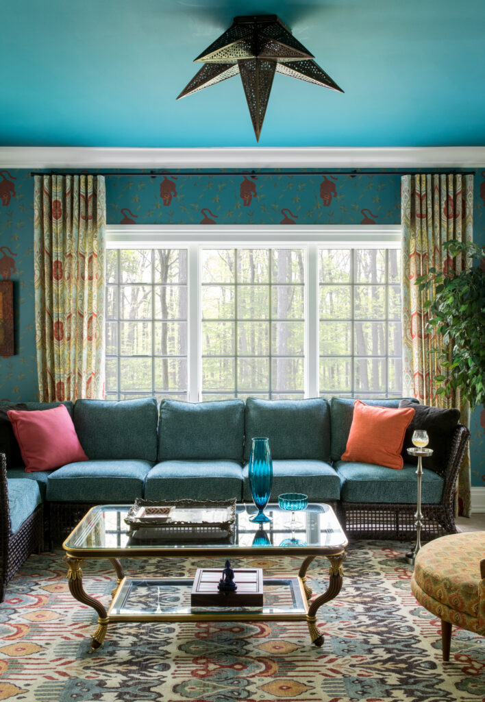 The patterned walls, curtains, fabric chair and carpet all layer over one another to create a maximalist effect.