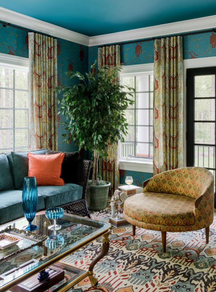 The patterned walls, curtains, fabric chair and carpet all layer over one another to create a maximalist effect.